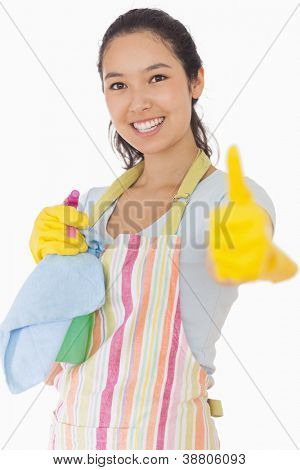 Mulher sorridente no avental, mantendo produtos de limpeza, desistindo de polegares