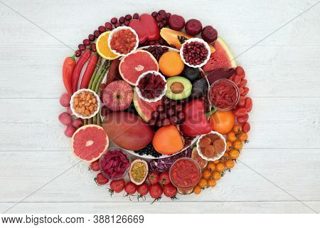Immune boosting health food high in lycopene, anthocyanins, antioxidants, vitamins, minerals & dietary fibre. With fruit & vegetables in a circular design on a plate & loose on rustic wood. 