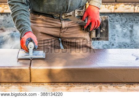 Construction Worker Using Hand Groover On Wet Cement Forming Coping Around New Pool.