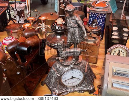 Flea Market Merchandise Out On Street - Old Silver Clock With Girl Walking A Dog, Wooden Pipe Set, C
