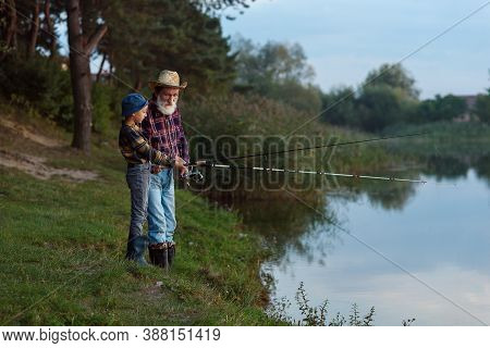 Stylish Experienced Bearded Grandpa In Straw Hat Fishing Together With His Curious Grandchild On The
