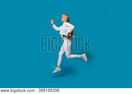 Running Blonde Woman Is Holding A Present Box On A Blue Studio Wall And Smile In Casual Clothes