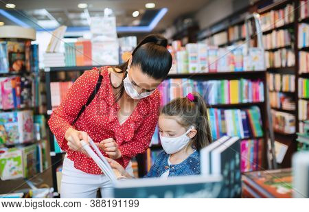 Mother And Daughter With Face Mask Shopping In Bookshop, Coronavirus Concept.