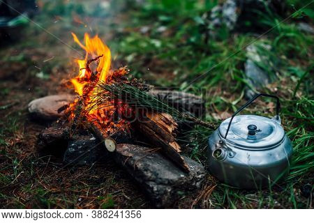 Camping Kettle Near Small Camp Fire Close-up. Cozy Camping Place In Wild. Wonderful Evening Atmosphe