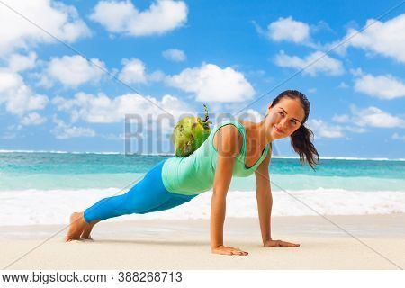 At Sea Beach Active Woman Doing Fitness Exercises Plank, Push Up With Coconut On Back To Keep Fit. B