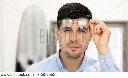 Poor Eyesight Concept. Portrait Of Handsome Young Man With Spectacles Squinting, Trying To Look Clos