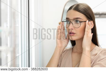 Choosing Glasses Concept. Portrait Of Beautiful Lady Picking New Eyewear At Optics Store, Looking At