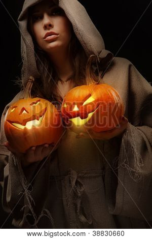 Köntös nő fejét tartja a halloween pumpkins köré