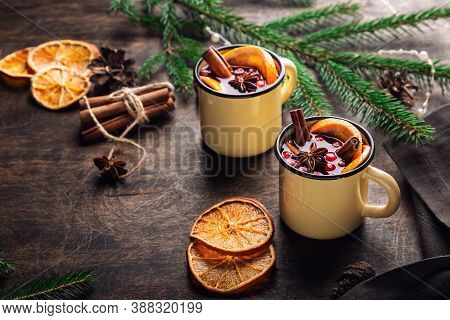 Christmas Mulled Wine With Cranberries, Orange And Spices In Mugs On Rustic Plywood Background. Trad