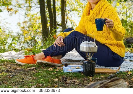Young Beautiful Girl In A Yellow Sweater Makes Coffee In The Forest On A Gas Burner. Making Coffee O
