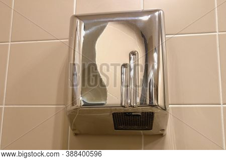 Metal Hand Dryer On The Tiled Wall. Hot Air For Drying Hands On The Wall With Tiles. Drier In Public