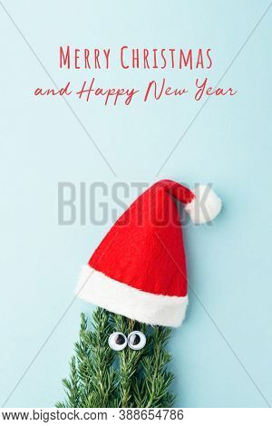 Concept Of Christmas Tree In Santa Clauss Hat On Blue Background. New Year Greeting Card.