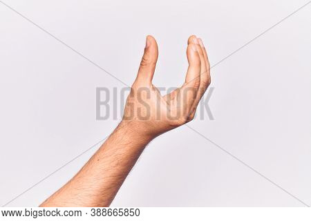 Close up of hand of young caucasian man over isolated background picking and taking invisible thing, holding object with fingers showing space 