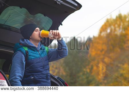 Close-up Of A Man Sitting On The Trunk Of His Car In The Forest. Male Camping In The Forest, Drinkin