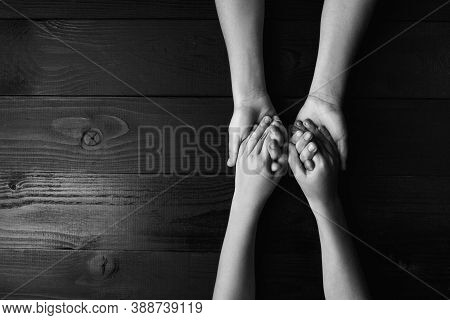 Top View Arms Stretches Out And Holds One Another On Black Wooden Background. Joint Support And Assi