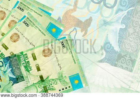 2000 Kazakhstani Tenge Bills Lies In Stack On Background Of Big Semi-transparent Banknote. Abstract 