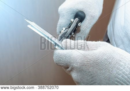 Worker In Gloves Cuts Profile For Stretching Ceiling, Cuts It With Metal Shears. Construction Work, 