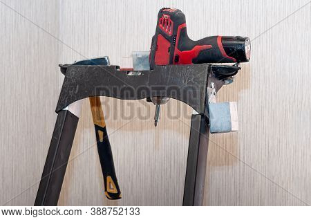 Electric Screwdriver And Hammer On Metal Ladder. The Renovation Of The House. Home Repairs. Construc