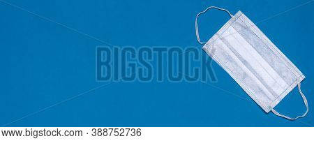 Protective Disposal Medical Mask On A Blue Background. Top View. Copy Space. Place For Text. Banner.
