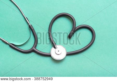 Stethoscope In Shape Of Heart Isolated On Green Background.