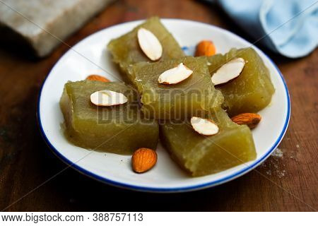 Indian Homemade Dessert Wheat Halwa Garnished With Badam On A Colorful Background