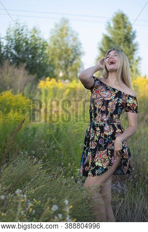 Overlight Bright Portrait Of A Charming Attractive Blonde In Flowery Dress In The Field
