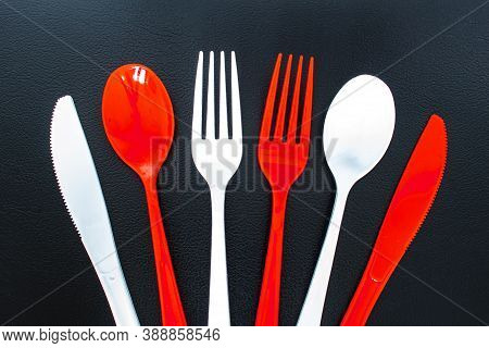 Single Use Red And White Plastic Cutlery On A Leather Background. Concept: Ban Single Use Plastic