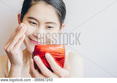 Portrait Of Happiness Asian Woman Applying Foundation Powder Puff On Her Face To Cover Flaws And Cha