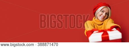 Caucasian Woman With Blonde Hair Wearing A Nice Hat Is Giving At Camera A Present Box Smiling And Ad