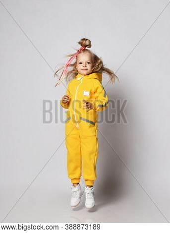 Full-growth Portrait Of Blonde Kid Baby Girl With Modern Hairstyle And Colorful Braids Wearing Styli