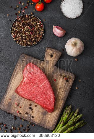 Slice Of Raw Beef Sirlion Steak On Wooden Chopping Board With Tomatoes,garlic And Asparagus Tips On 