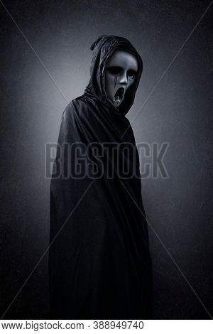 Ghostly figure in hooded cloak in the dark