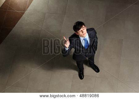 Image of young businessman with his eyes closed thumb up. Top view