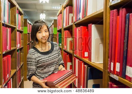 Thai College Girl Is Holding Stack Of Books .