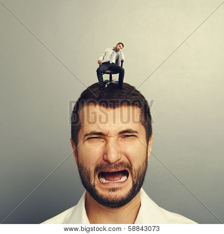 portrait of sad screaming man with small bored man on the head