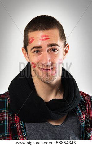 Portrait of young man with face full of lipstick marks of kisses