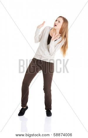 Beautiful casual woman is crouching from sth heavy above her. Isolated on white.