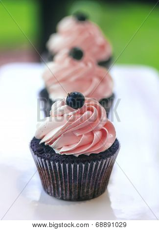 Chocolate cup-cake with pink whipped cream on white plate