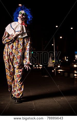 Crazy ugly grunge evil clown in town on Halloween making people shock and scared