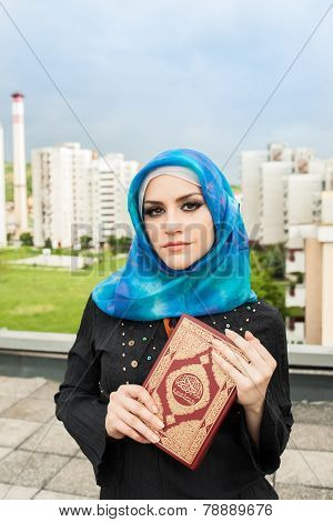 beautiful muslim woman wearing hijab and holding holy book Koran