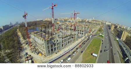 Construction site with lots of cranes next to the road, aerial view