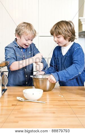 Kids having fun during a baking workshop, whisking dough in a stainless steel bowl during a birthday party