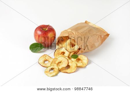 fresh red apples and dried apple rings spilt out of paper bag