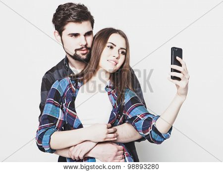 tehnology, internet, emotional  and people concept: Capturing happy moments together. Happy young loving couple making selfie and smiling while standing against white background.