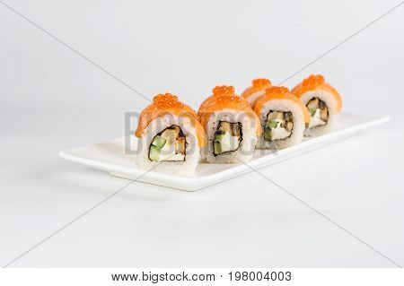 Sushi Rolls With Salmon, Avocado And Cream Cheese, Decorated With Red Caviar, Served On White Slate.