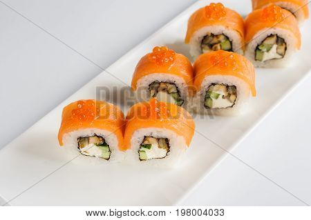Sushi Rolls With Salmon, Avocado And Cream Cheese, Decorated With Red Caviar, Served On White Slate.