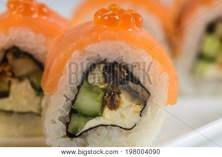 Sushi Rolls With Salmon, Avocado And Cream Cheese, Decorated With Red Caviar, Served On White Slate.