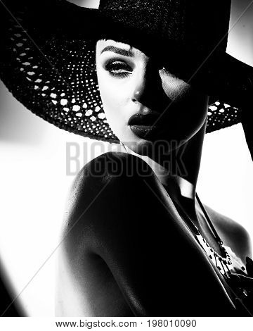 fashion concept - portrait of a beautiful woman in big hat and sunglasses in mixed contrast light