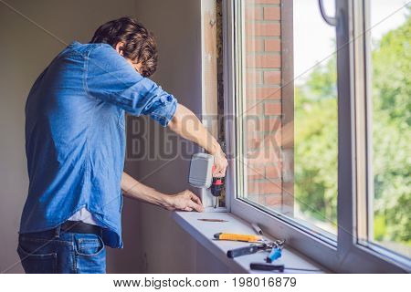 Man In A Blue Shirt Does Window Installation