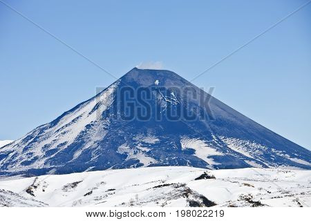 The current cone of Karymsky volcano on the Kamchatka Peninsula in spring. The view from the helicopter over the volcano. Russia